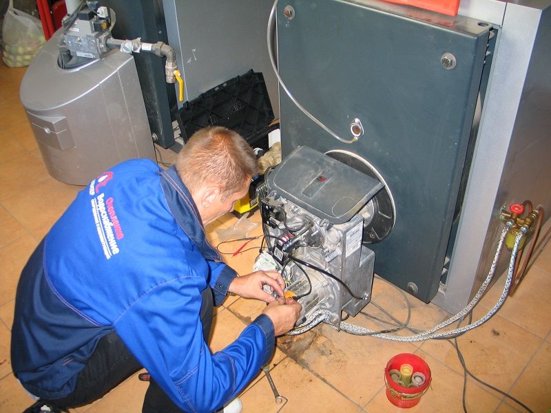 мастер ремонтирует напольный газовый котел